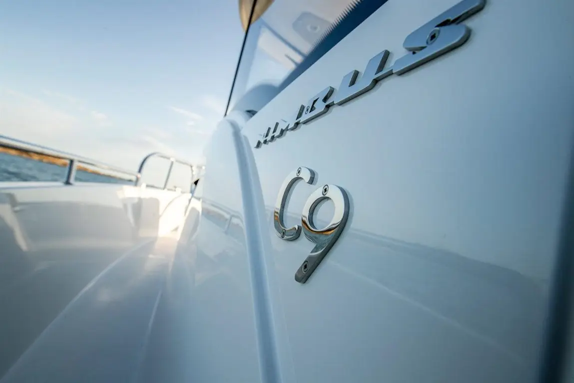 Close-up of a boat's side featuring the name "Marquis" and the model "C9" in chrome lettering against a sleek white surface.